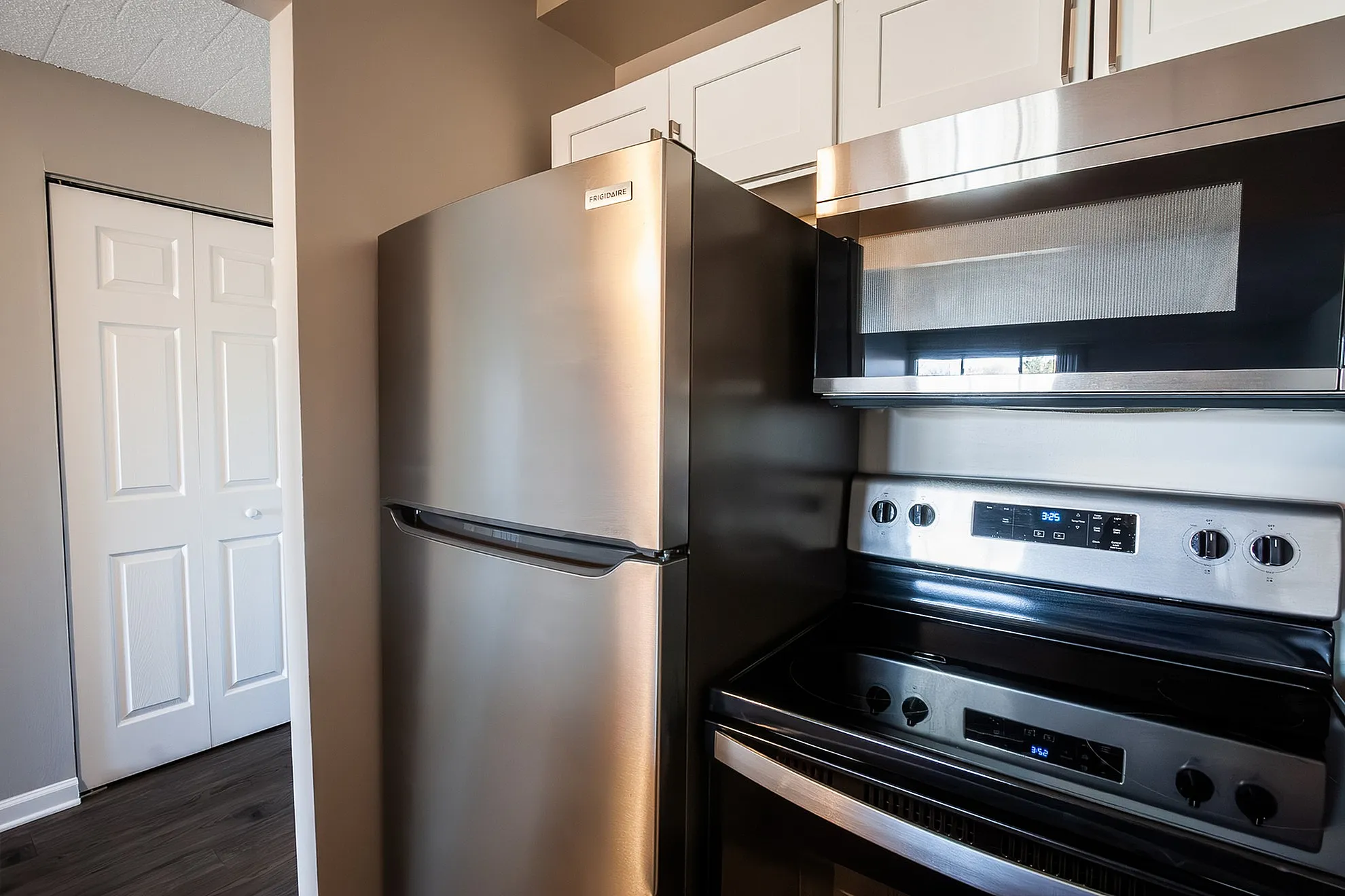 Modern kitchen featuring sleek stainless steel appliances, including a refrigerator and oven, with stylish cabinetry and dark hardwood floors.