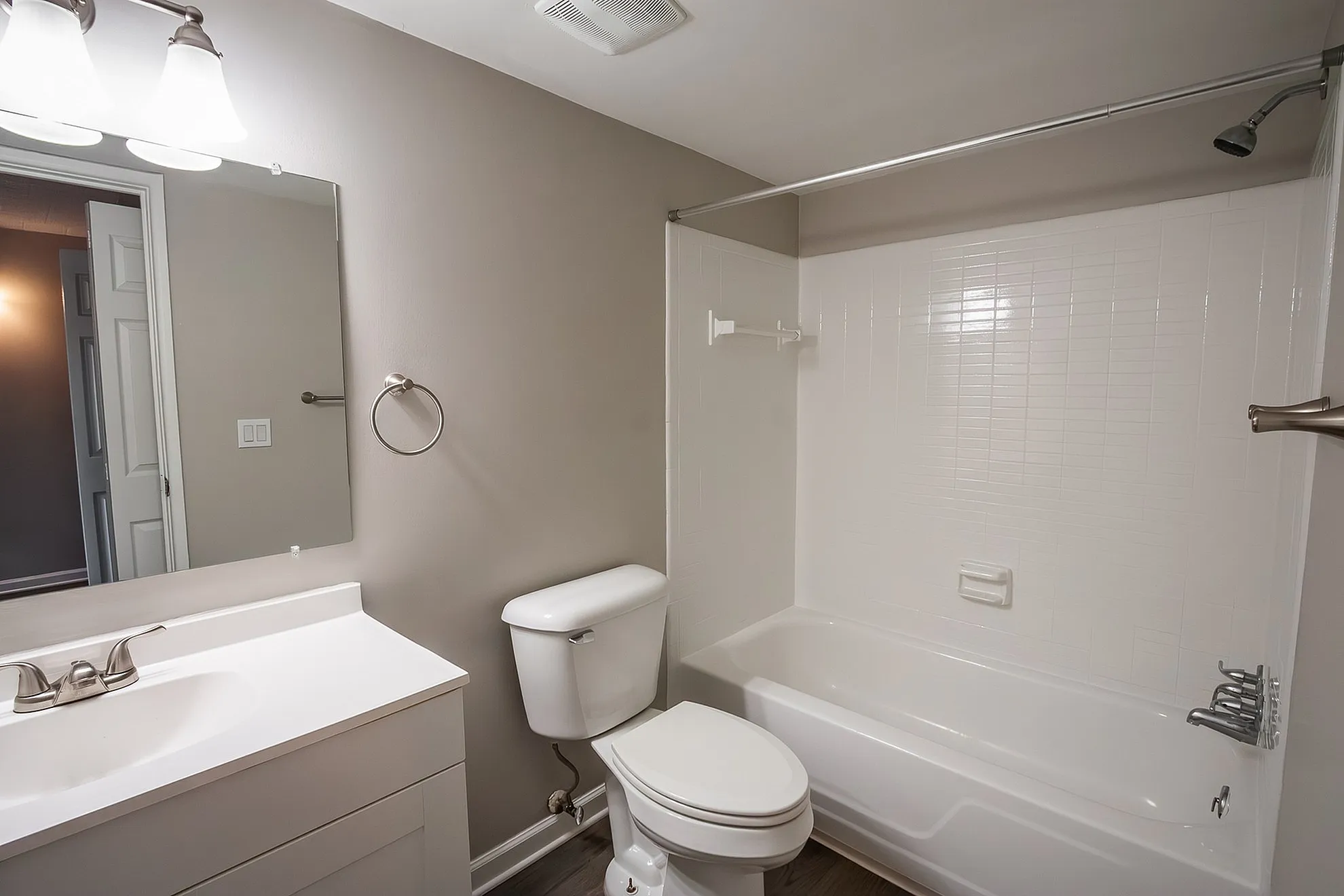 Elegant and contemporary bathroom featuring a pristine white vanity, modern sink, spacious mirror, and relaxing bathtub with shower.