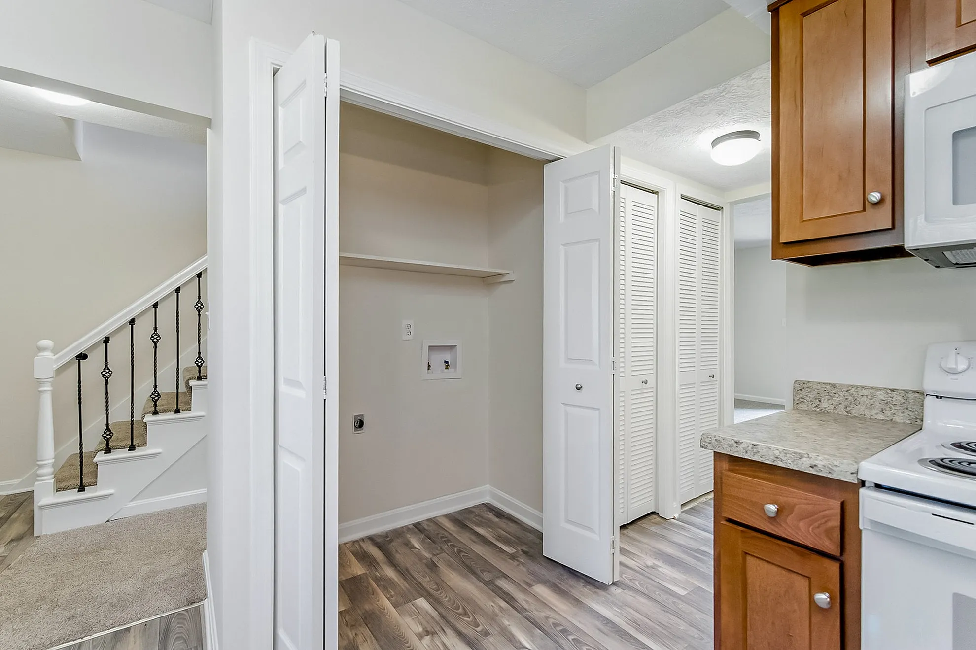Inviting apartment interior showcasing modern kitchen, elegant staircase, and ample storage spaces.