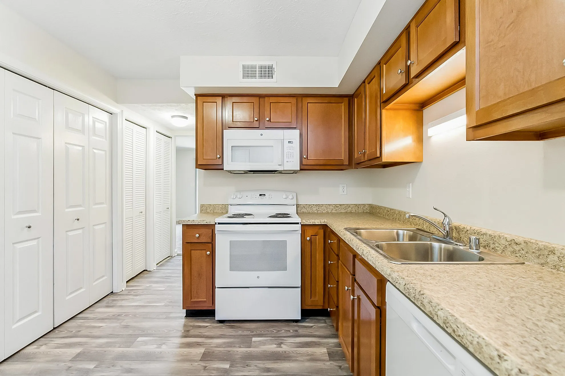 Bright and modern kitchen featuring elegant wooden cabinets, sleek appliances, and spacious countertops.