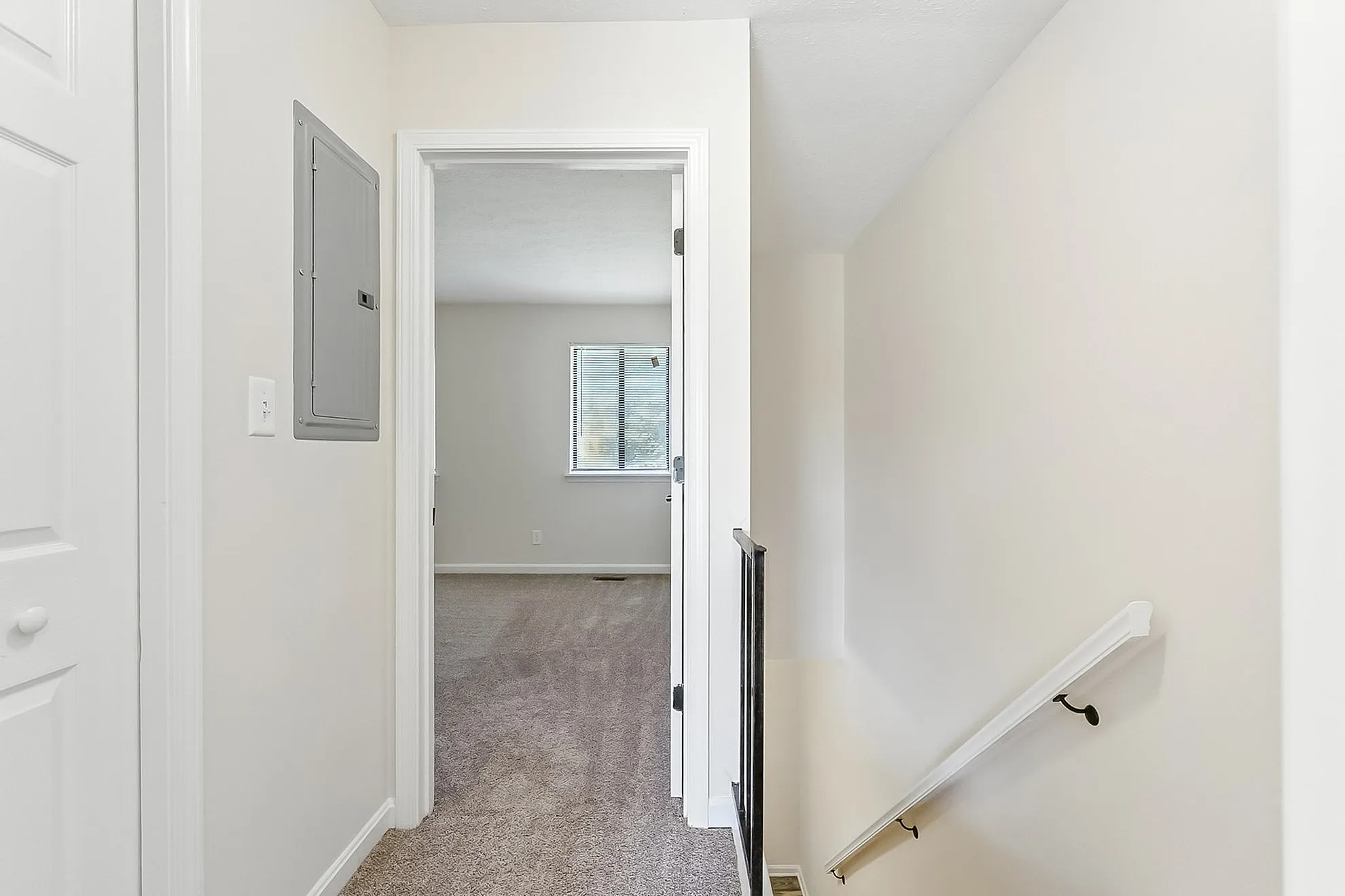 Bright hallway with neutral colors leading to a cozy carpeted room, perfect for a serene living space.