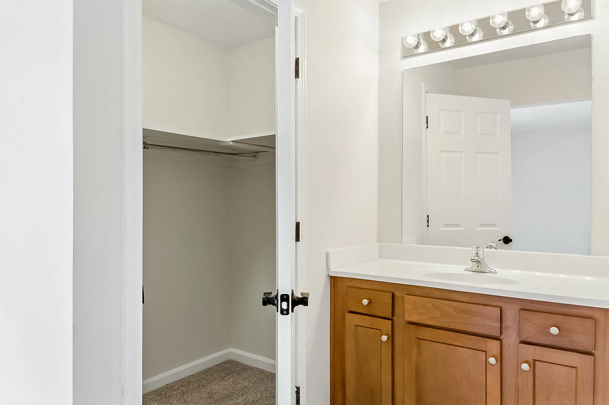Bright and inviting bathroom with elegant wooden vanity and spacious closet, ideal for modern living.