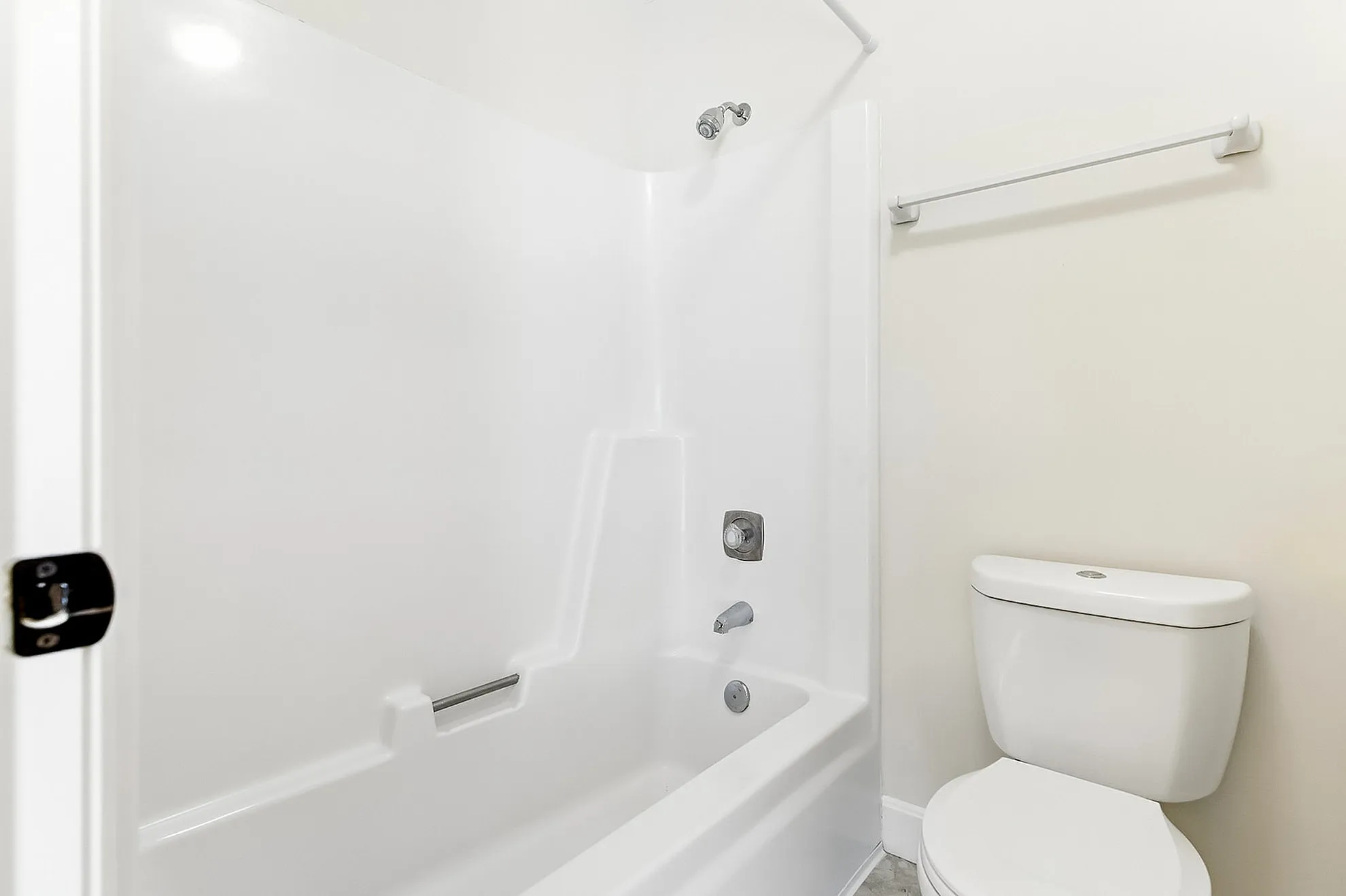 Elegant bathroom featuring a pristine white bathtub and modern toilet, accented by clean lines and neutral tones.