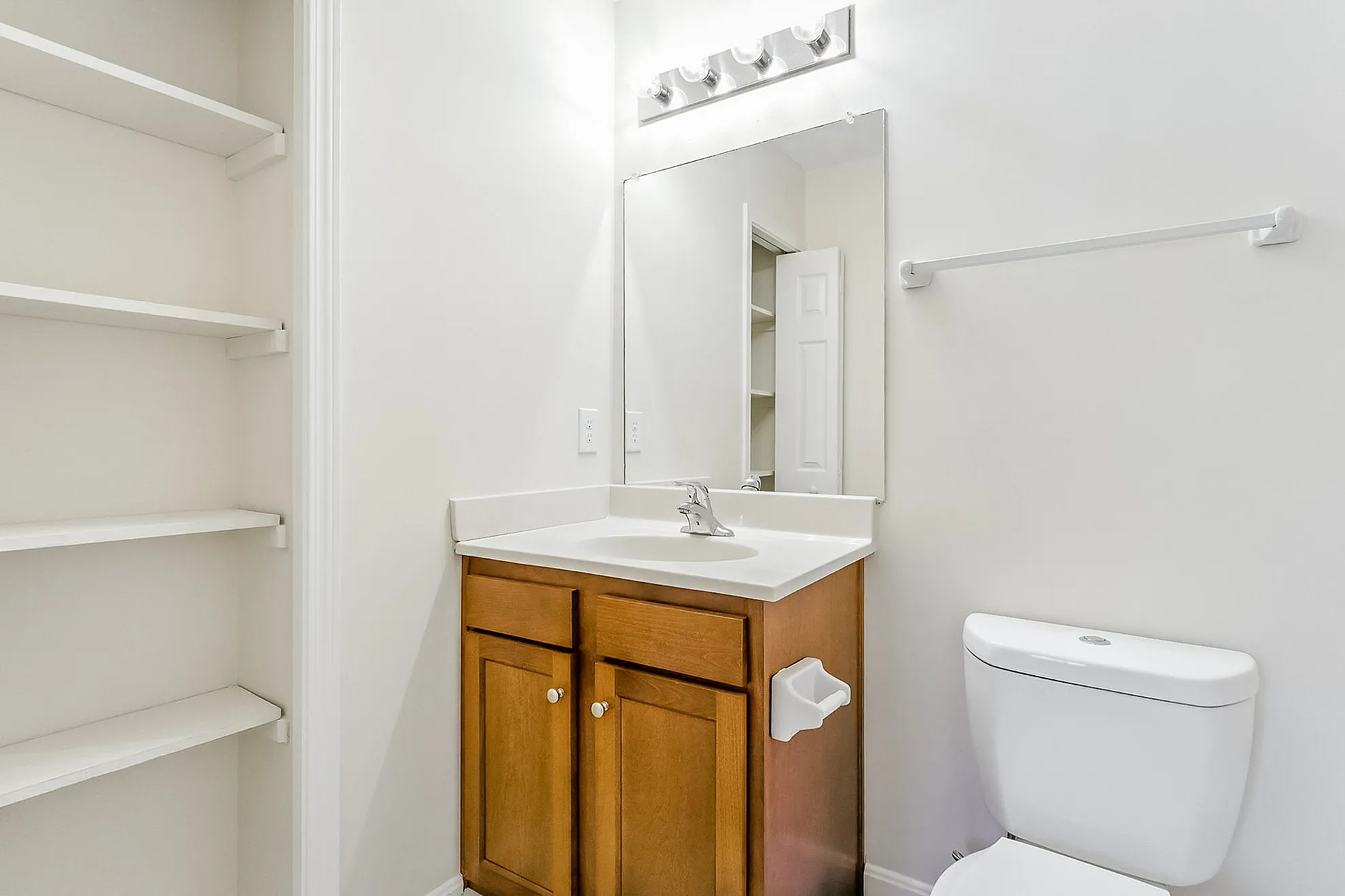 Charming bathroom with elegant white shelves, a sleek vanity, and contemporary lighting for a modern touch.