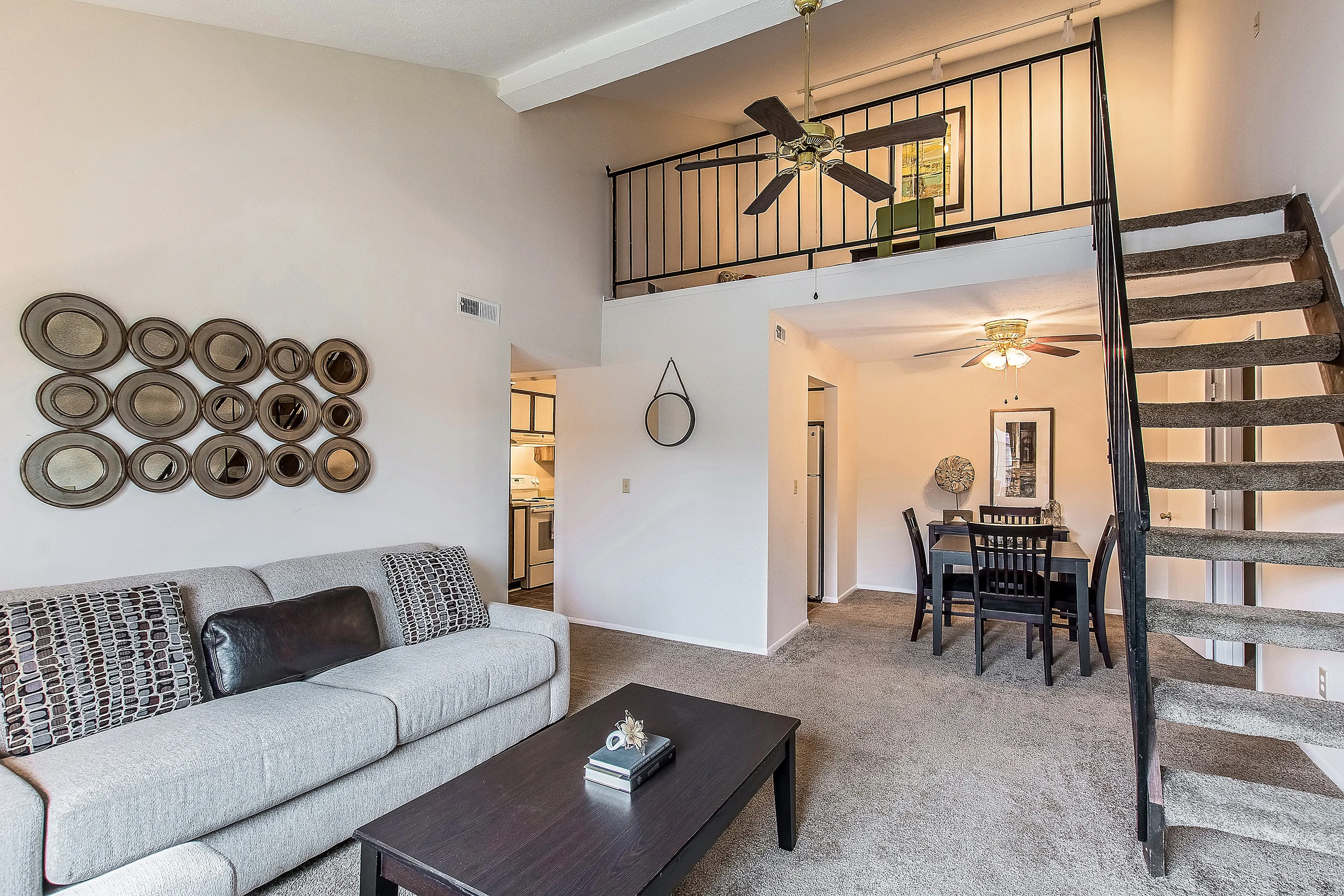 Chic living space with modern loft design, featuring a cozy seating area, stylish spiral staircase, and elegant dining setup adjacent to a compact kitchen.