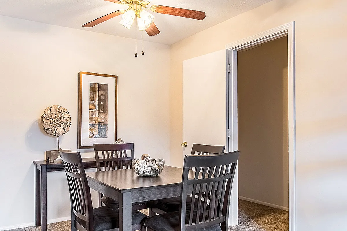 Inviting dining area with elegant wooden table and chairs under a stylish ceiling fan, complemented by tasteful wall art.
