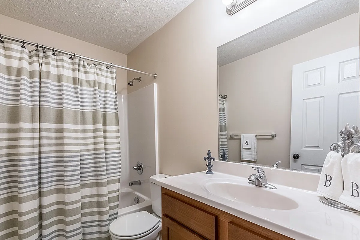Bright, contemporary bathroom featuring elegant fixtures, a clean vanity, and a stylish striped shower curtain.