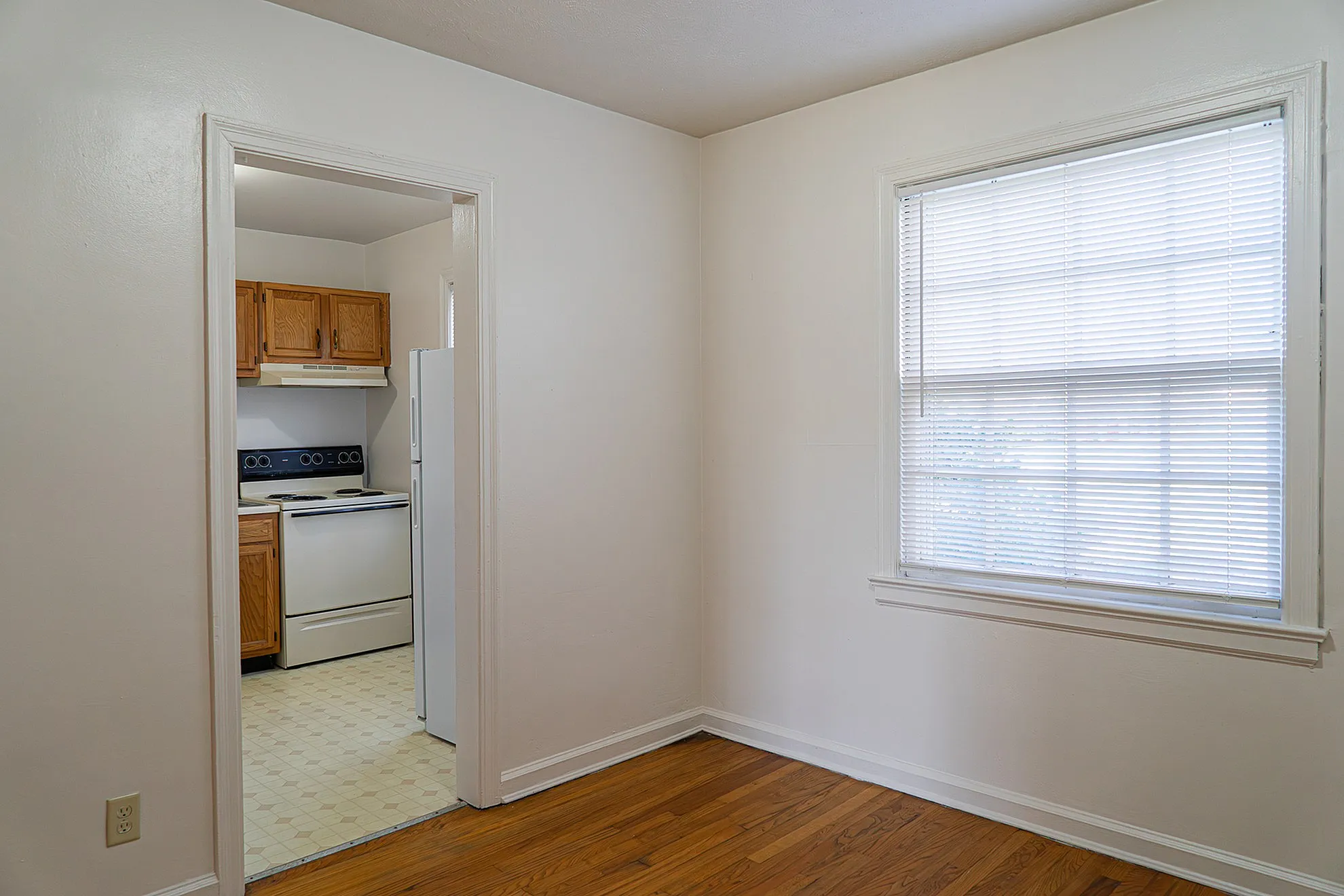 Inviting apartment with a cozy kitchen view, featuring wooden cabinets, a modern stove, and large window providing ample natural light.