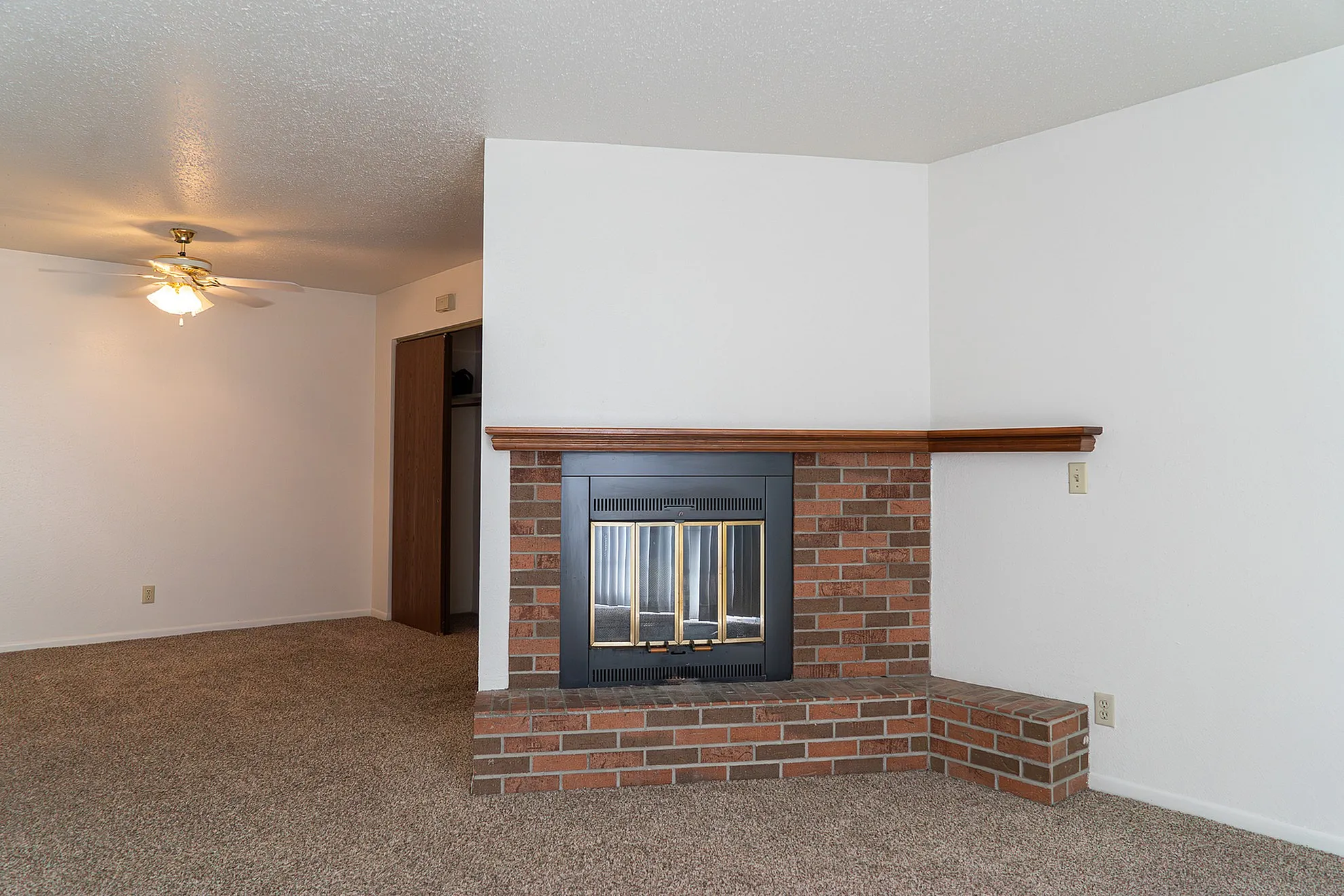 Inviting living room with a cozy brick fireplace and elegant ceiling fan, perfect for relaxing evenings.