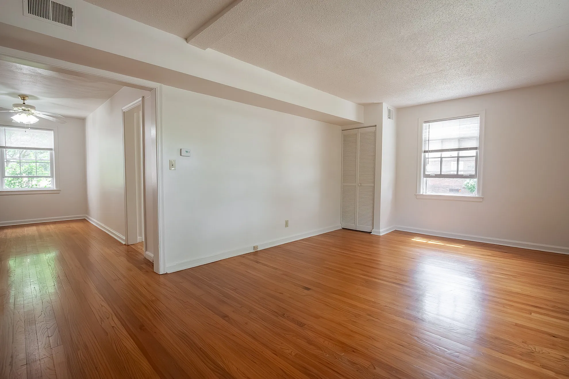 Bright and airy living space with rich hardwood floors and large windows, offering a cozy and inviting atmosphere.