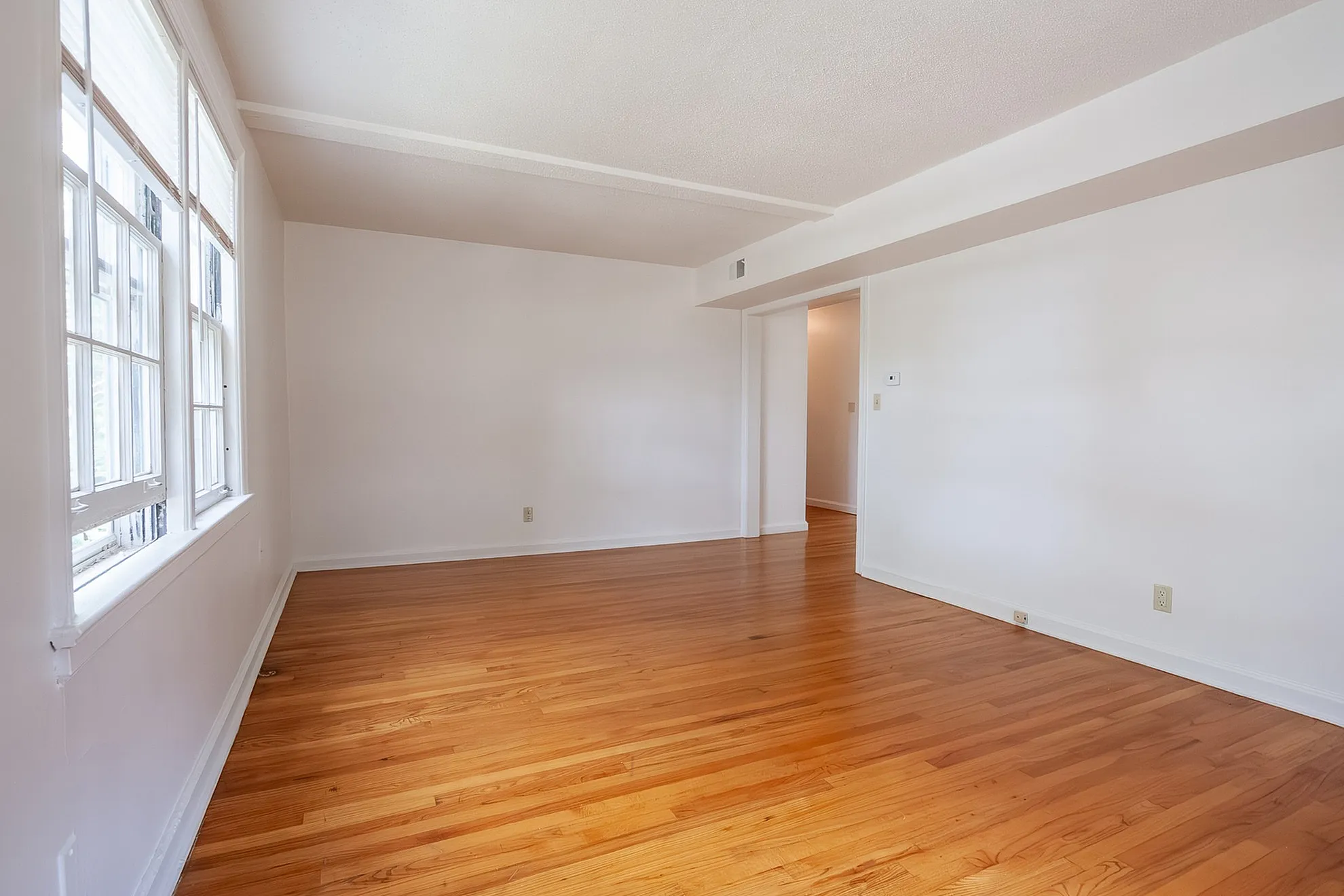 Bright and airy living space with beautiful hardwood floors and large windows, perfect for a cozy yet modern home setting.