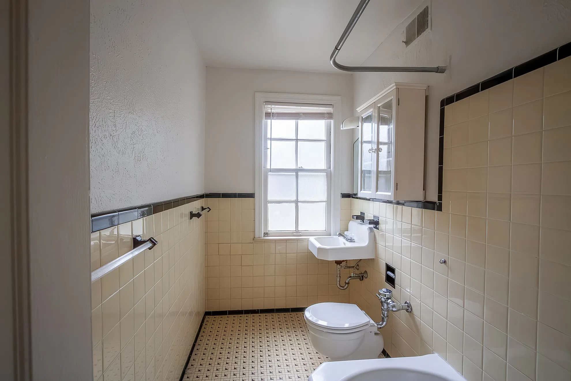 Modern bathroom with elegant beige tiles, radiant natural light through large window, and sleek fixtures for a serene atmosphere.