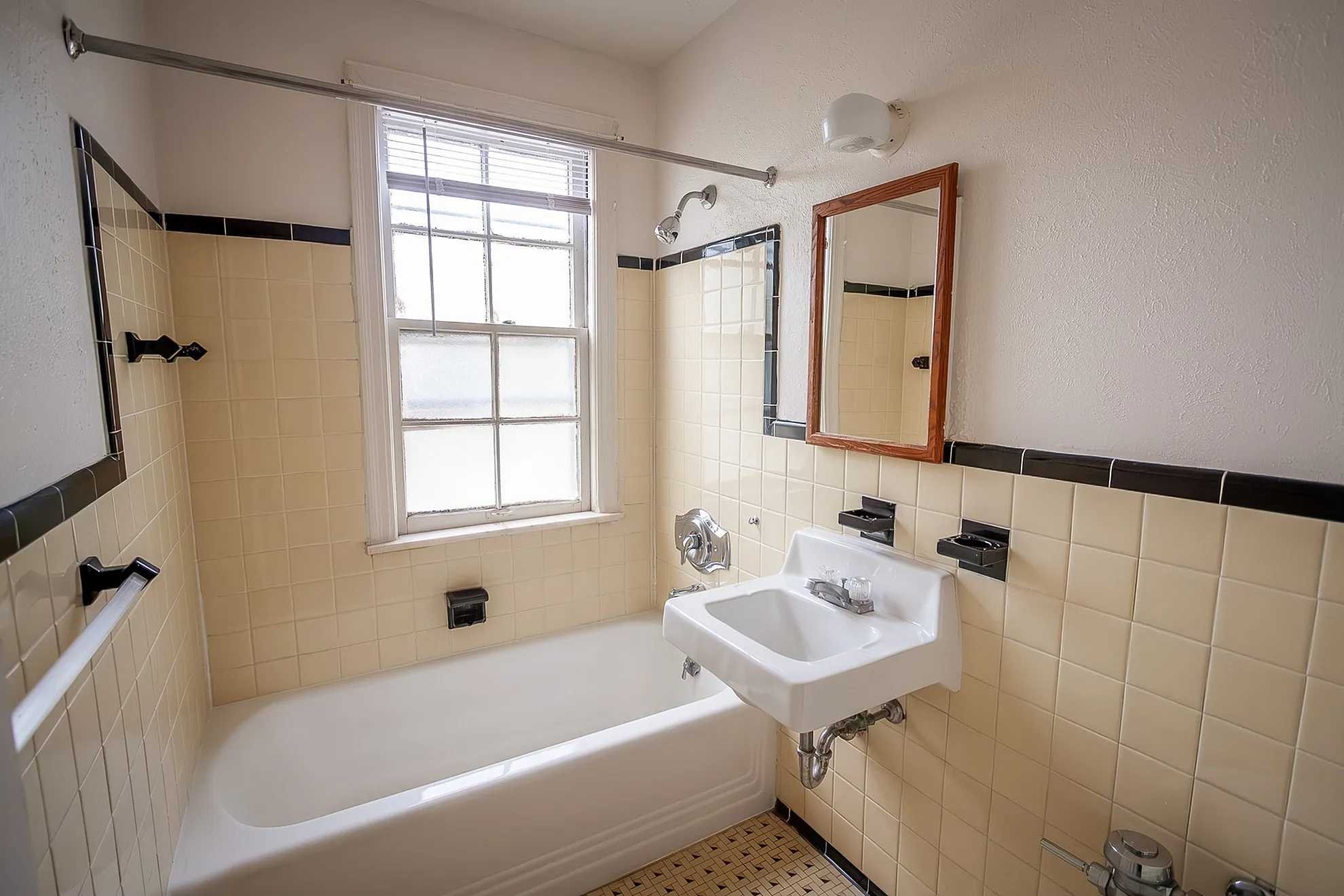 Charming vintage bathroom with stylish cream tiles, classic bathtub, and natural light through the large window.