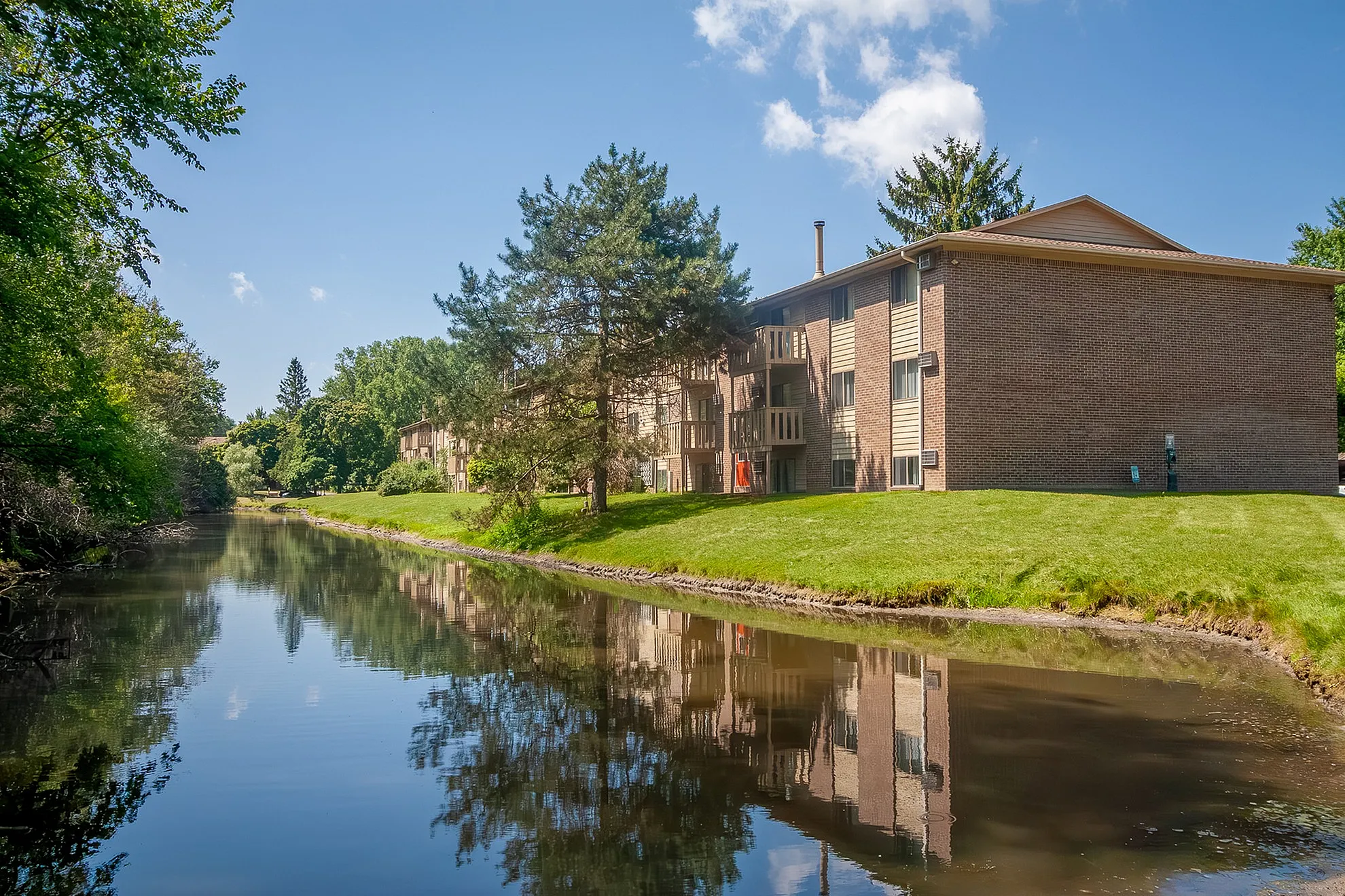 Charming riverside apartment complex surrounded by lush greenery, offering tranquil living and natural beauty.