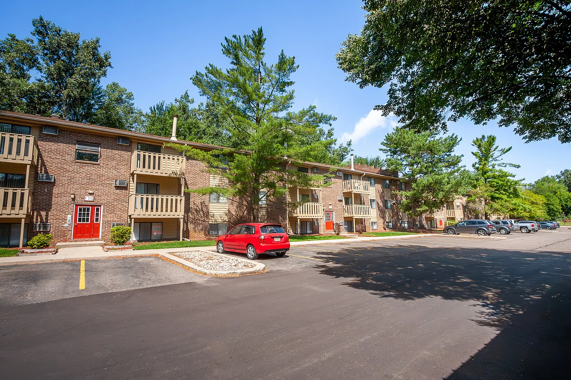 Vibrant apartment complex with stylish red doors, spacious balconies, and lush green surroundings.