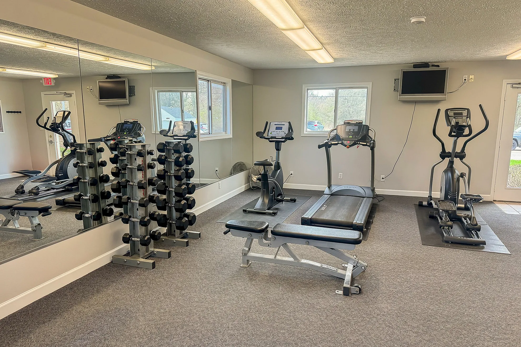 Modern fitness center featuring state-of-the-art equipment, including treadmills, ellipticals, and a comprehensive set of dumbbells.