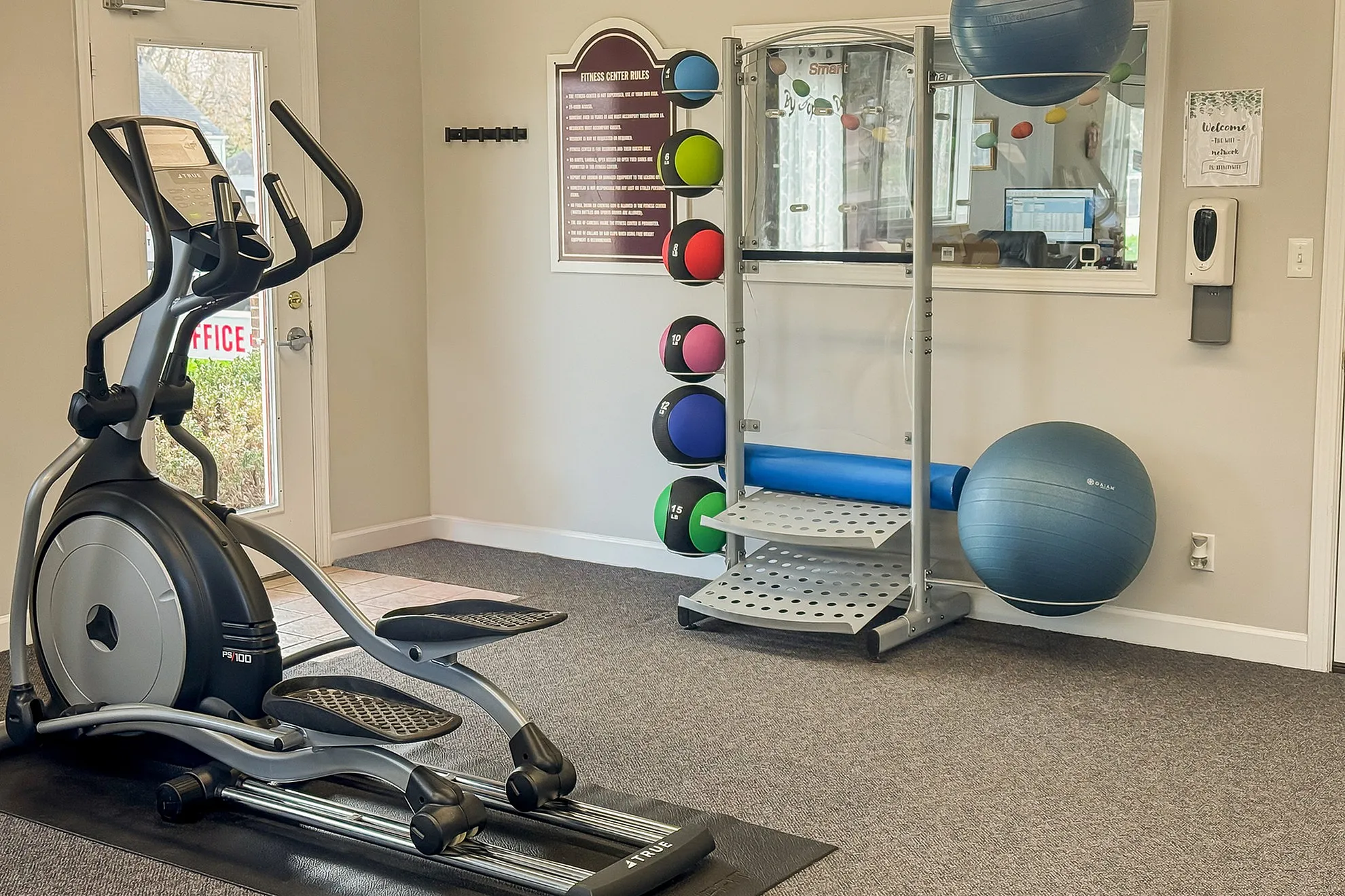 Bright and inviting fitness center featuring modern exercise equipment, colorful medicine balls, and a spacious area for workouts.