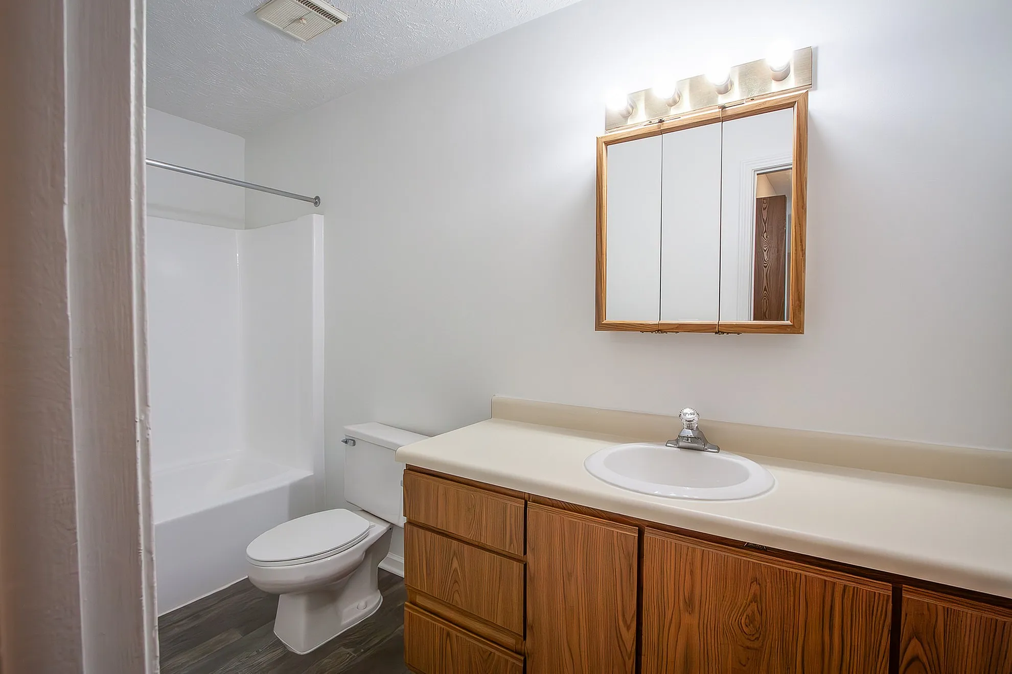 Bright and modern bathroom featuring a sleek vanity with a large mirror, elegant lighting, and a pristine bathtub.