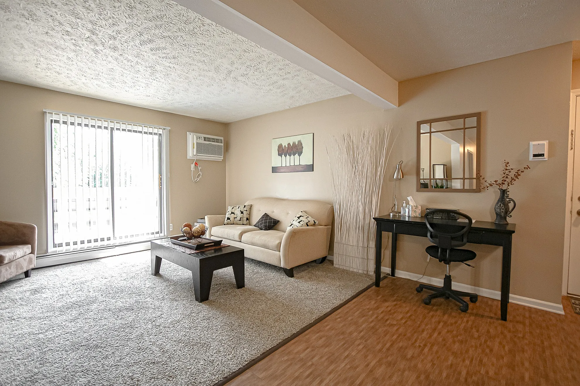 Bright and inviting living room with modern decor, featuring a comfortable beige sofa, sleek black coffee table, and natural light streaming in through large sliding glass doors.