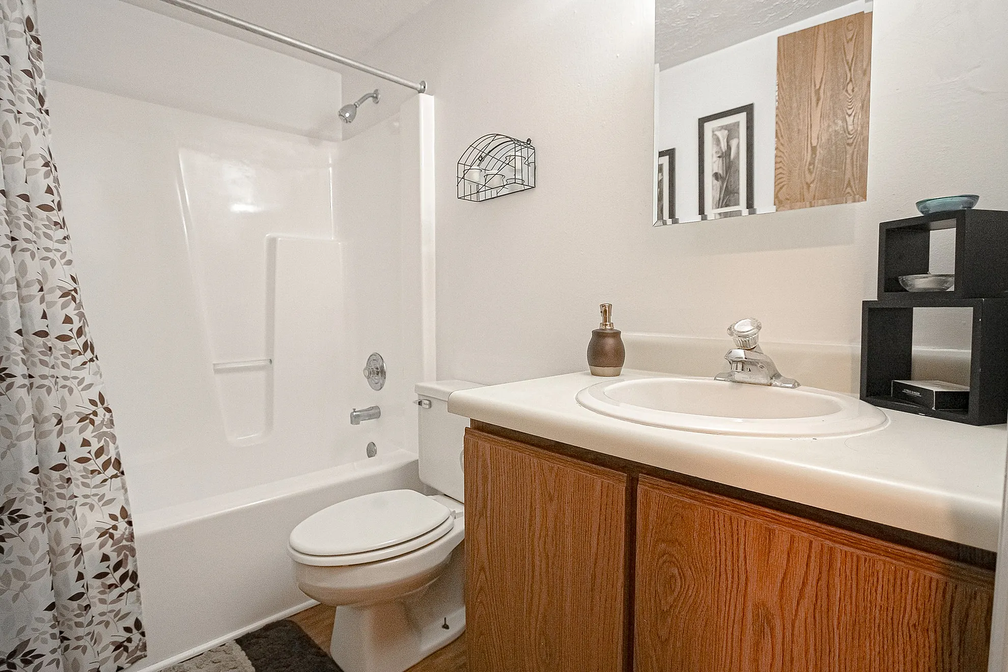 Modern apartment bathroom with elegant white countertop, stylish wooden cabinetry, and contemporary shower space.