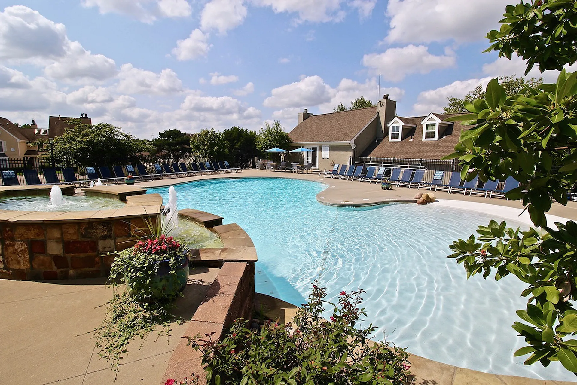 Luxurious outdoor swimming pool with elegant fountains and lush greenery, offering a perfect relaxing retreat.