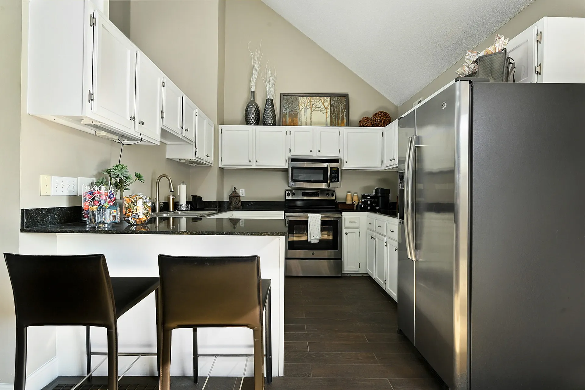 Modern kitchen with stainless steel appliances, sleek black countertops, and stylish bar seating for a cozy dining experience.