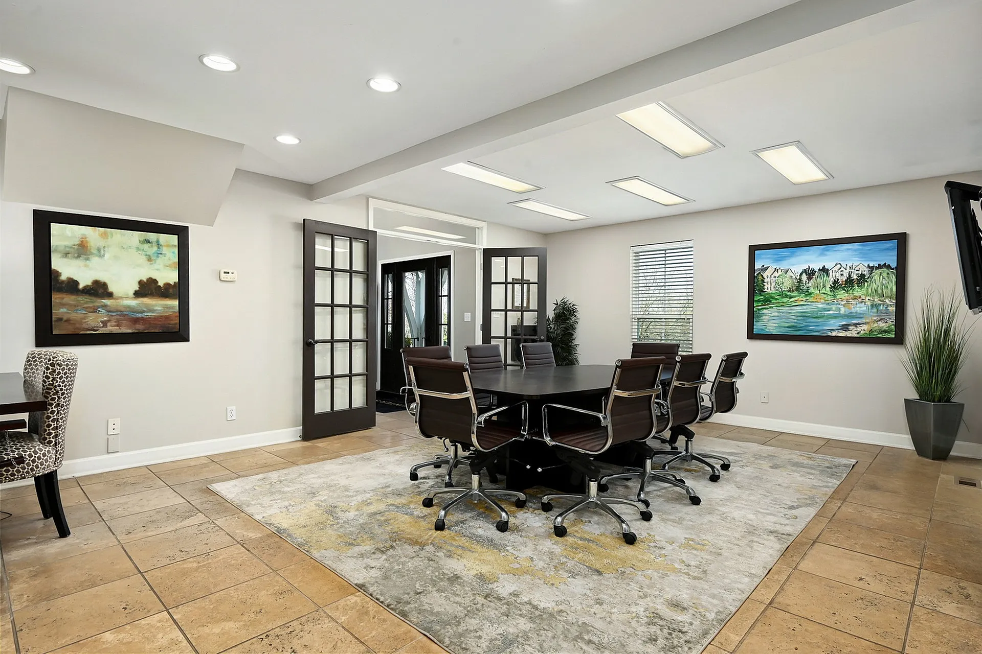 Modern conference room with elegant decor, featuring a large wooden table, stylish chairs, and beautiful artwork, offering a professional and welcoming atmosphere.