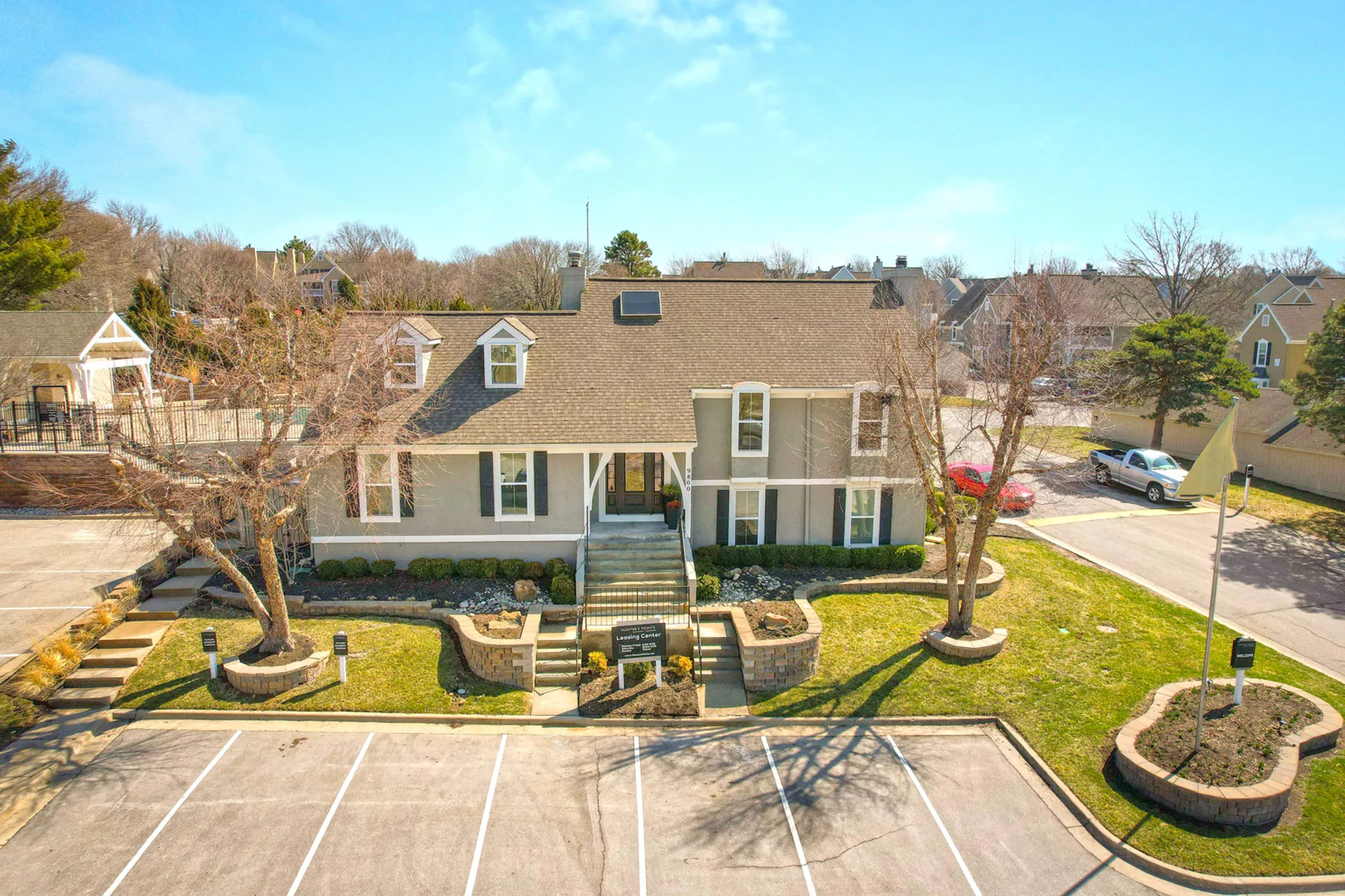 Charming residential building with a welcoming entrance, surrounding greenery, and ample parking space.