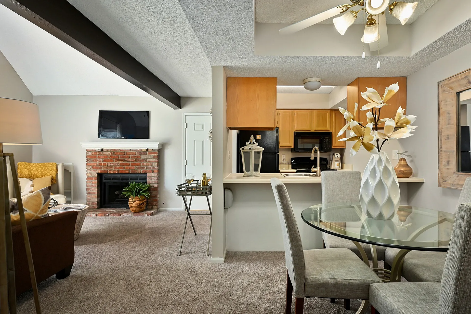 Inviting apartment interior featuring a cozy living room with a brick fireplace, modern kitchen, and elegant dining area accented with fresh decor and soft lighting.