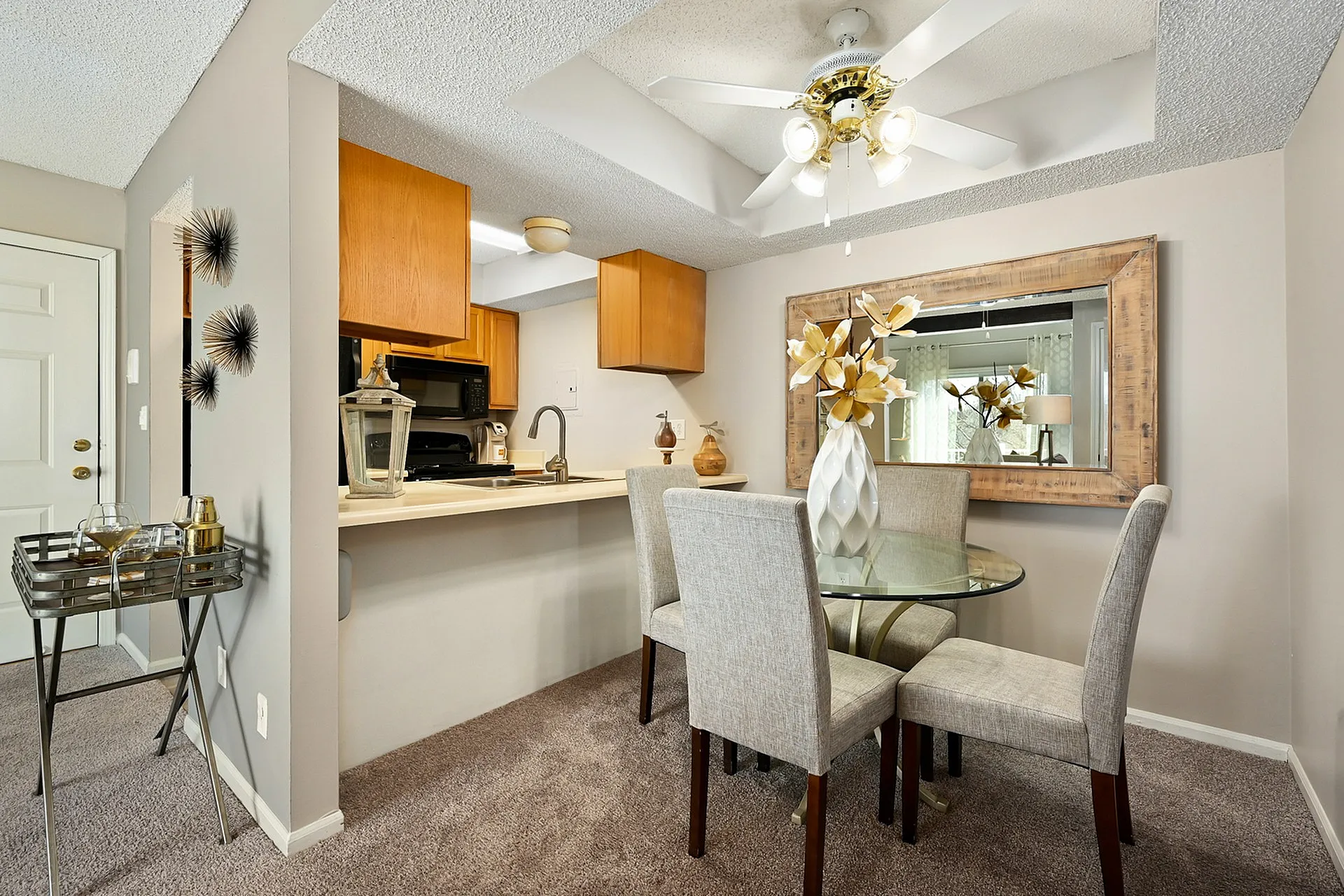 Charming dining area with elegant glass table, comfortable seating, and cozy carpet near an open kitchen layout.