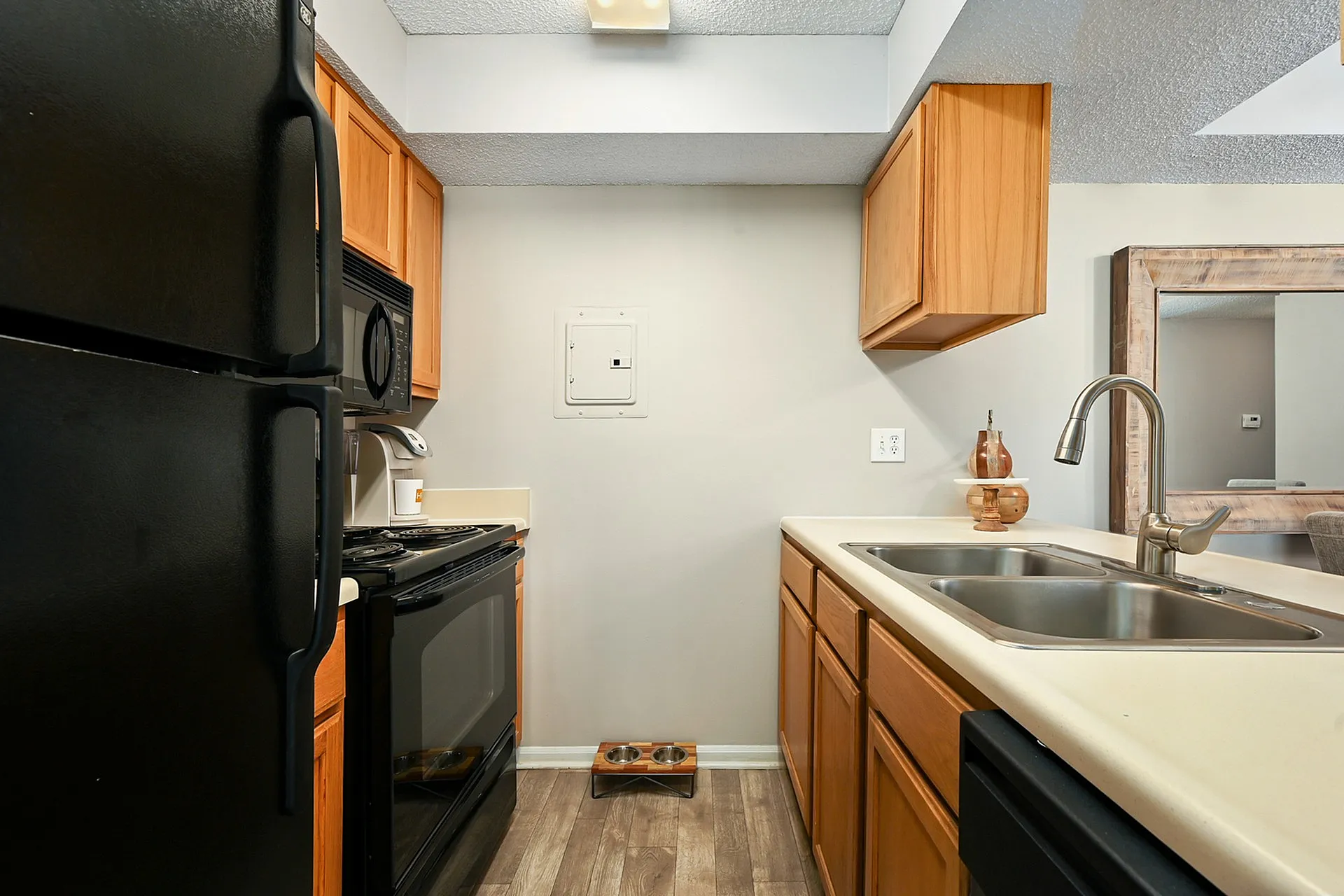 Cozy modern kitchen with sleek black appliances, wooden cabinetry, and a dual sink, perfect for culinary delights.