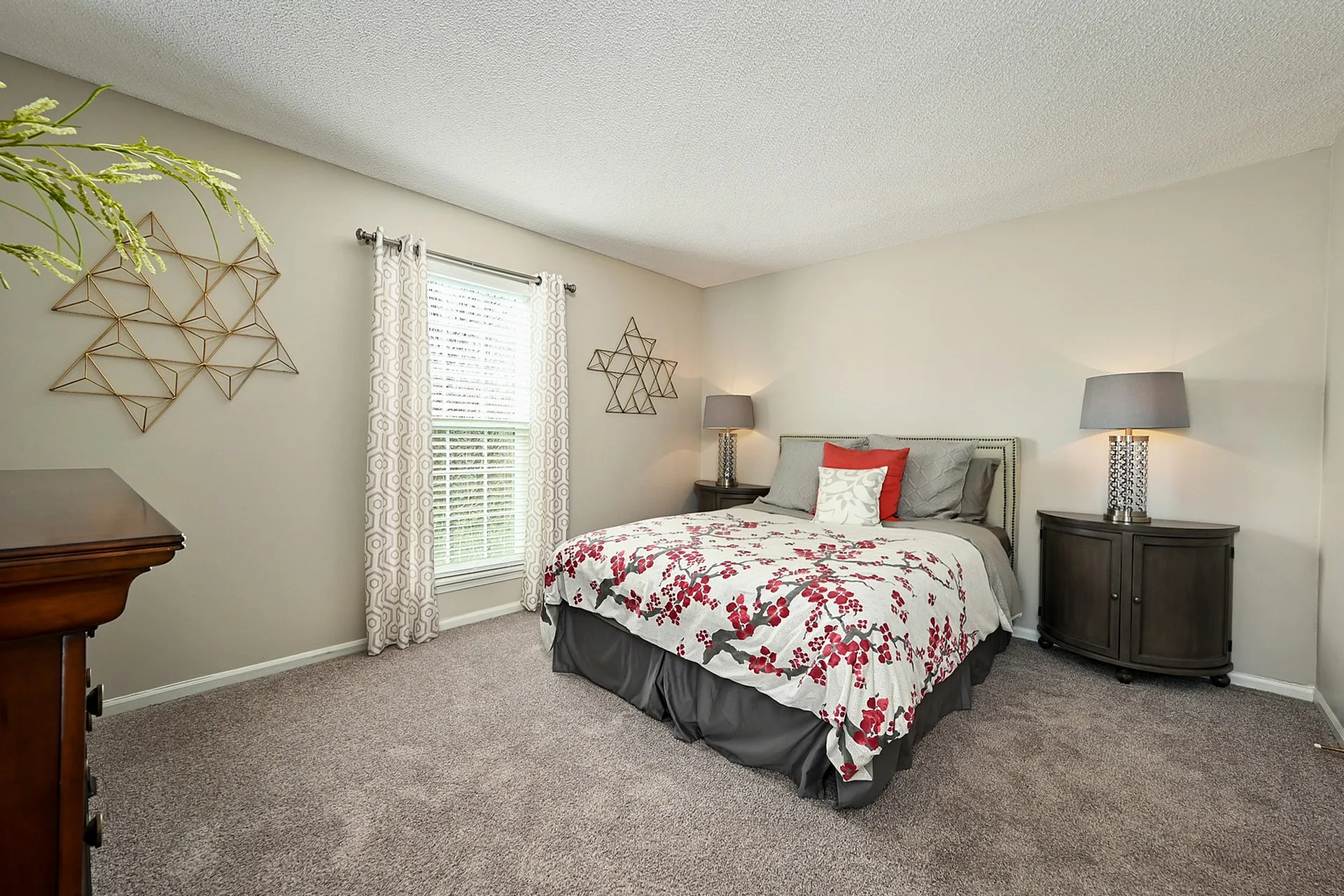 Inviting bedroom with a plush bed, elegant wall decor, and ample natural light from a large window.