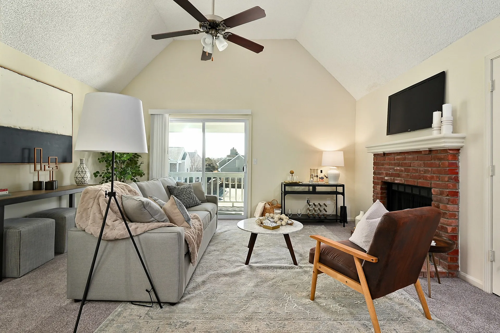 Charming living room with modern decor, featuring a cozy grey sofa, stylish brown armchair, and a rustic brick fireplace.