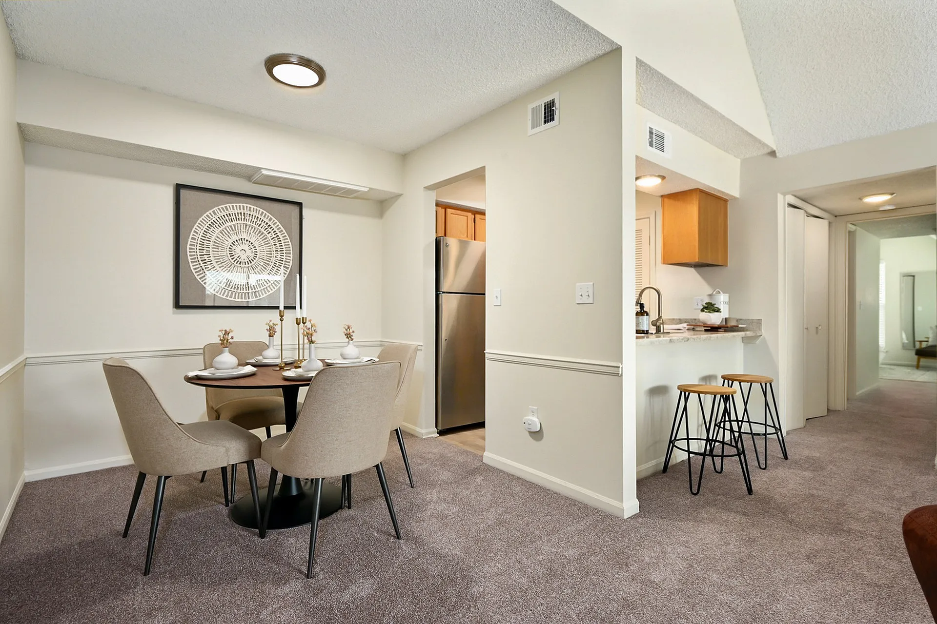 Charming dining area with elegant table setting, adjacent to modern kitchen with breakfast bar and stools.