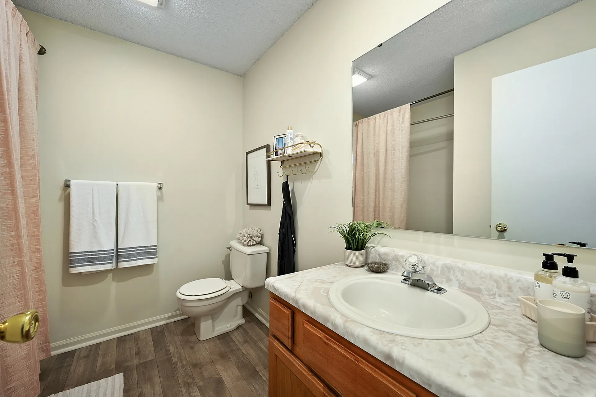 Modern bathroom with elegant fixtures, marble countertop, and warm wood cabinetry, featuring a cozy ambiance and stylish decor.