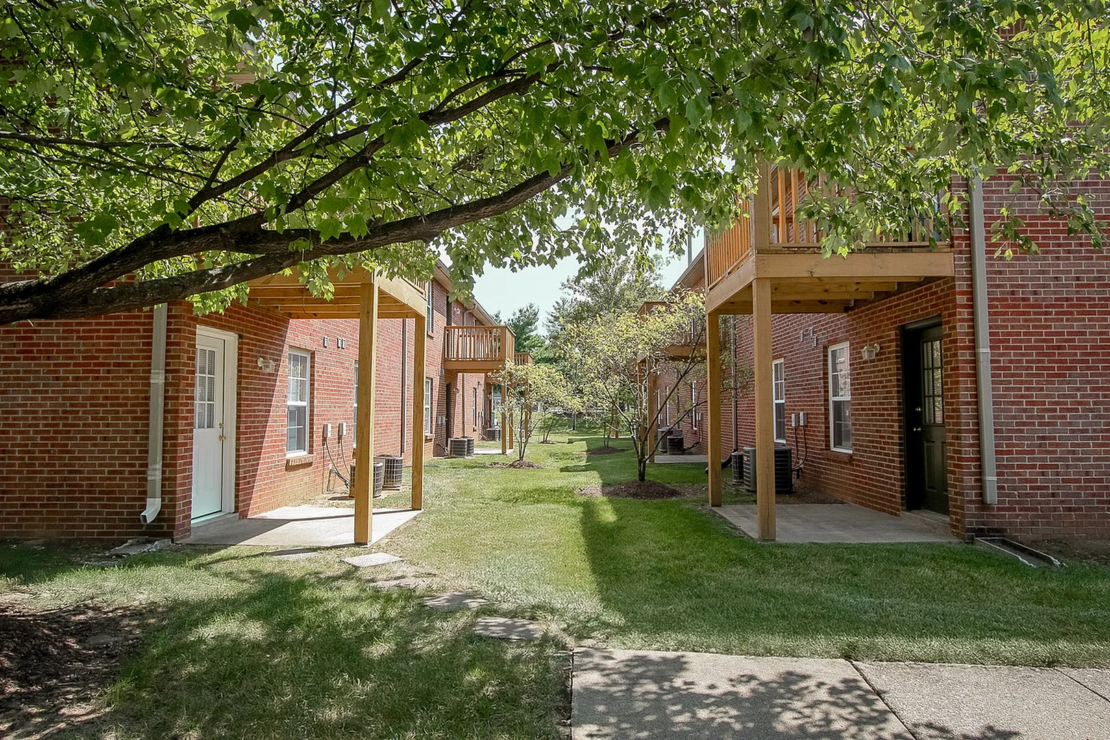Charming apartment buildings with red brick exteriors, overlooking a lush, green courtyard, perfect for relaxation.