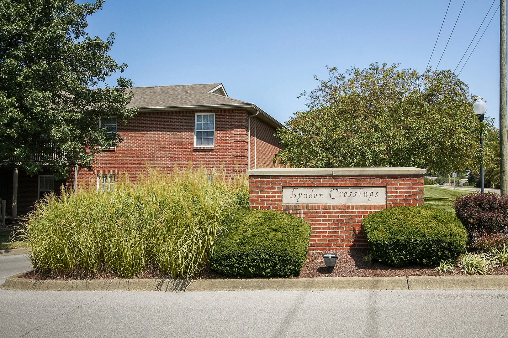 Charming brick entrance sign with lush landscaping at Lyndon Crossings apartment community.
