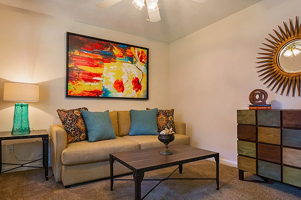 Chic living room with vibrant abstract art, cozy beige sofa, colorful cushions, and stylish geometric decor.