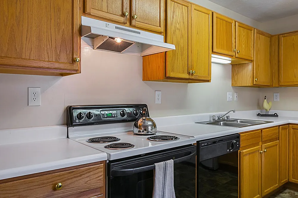 Modern kitchen with sleek white countertops, vibrant wooden cabinetry, and stainless steel appliances, offering a perfect blend of style and functionality.