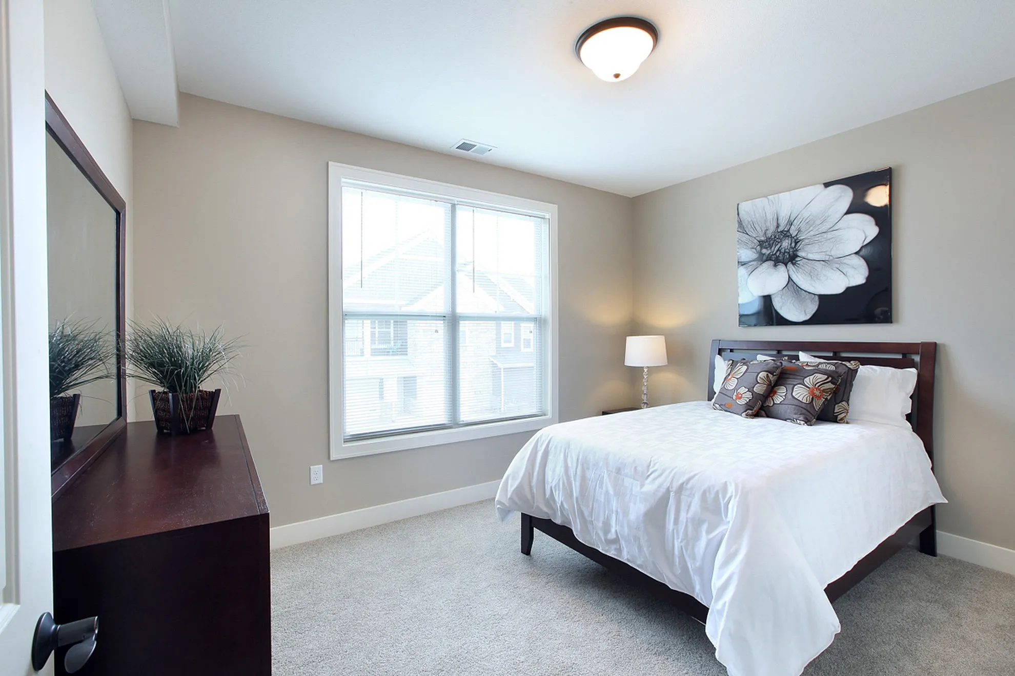 Bright and airy bedroom with modern decor, featuring large window, elegant bed, and stylish dresser.