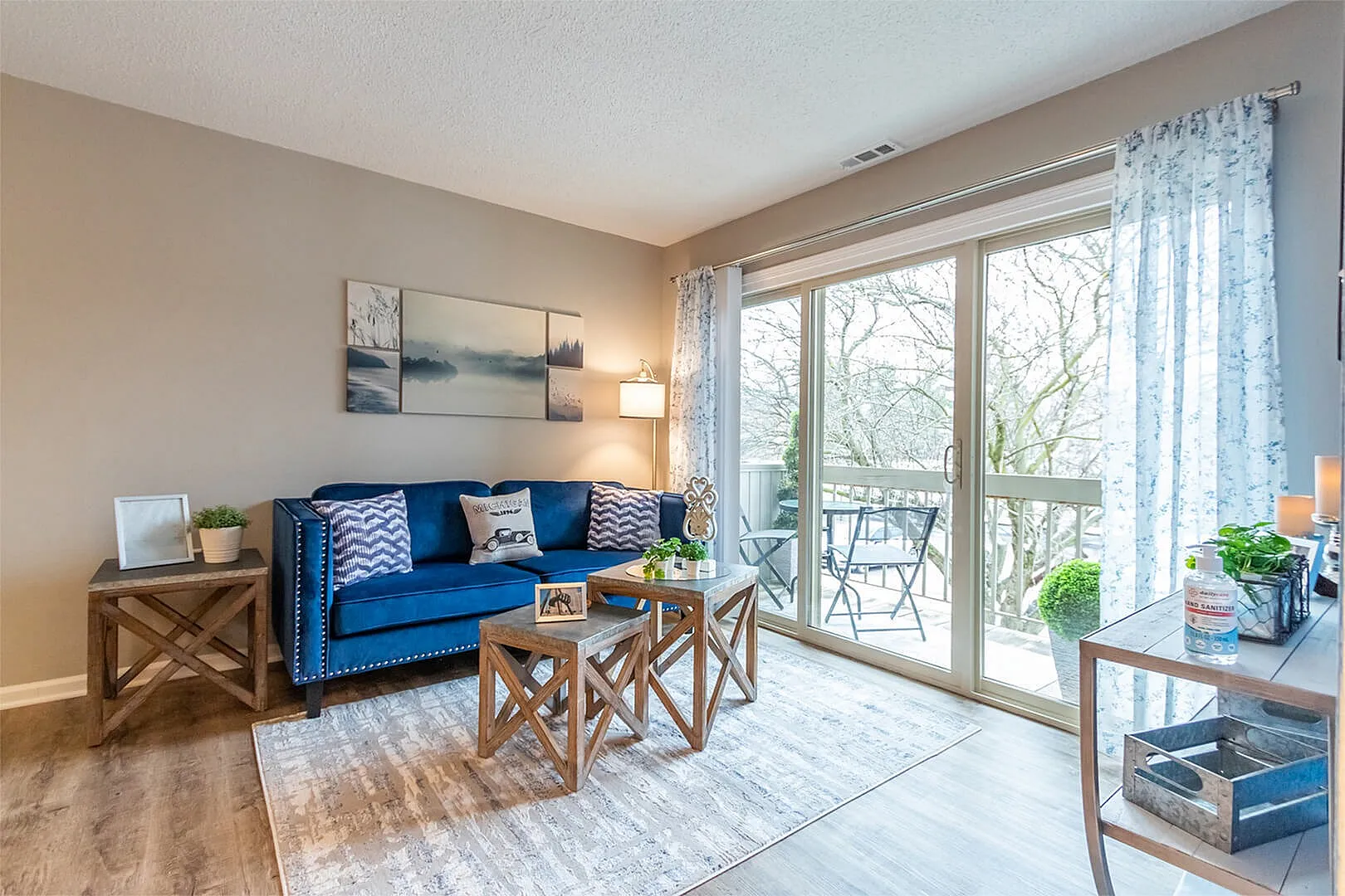Chic living room with vibrant blue couch, modern decor, and large glass doors leading to a serene balcony view.