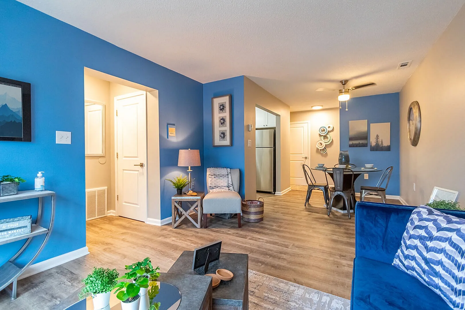 Inviting apartment interior featuring a vibrant blue accent wall, cozy seating area, and modern dining space with stylish decor.