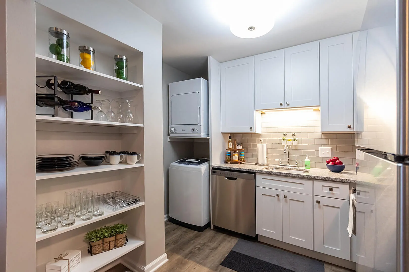 Modern kitchen with sleek white cabinets, integrated washer-dryer, and elegant shelving, perfect for stylish urban living.