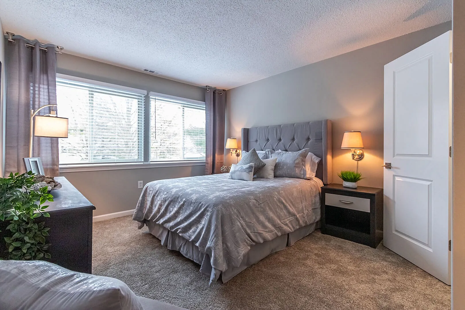 Inviting bedroom with elegant decor, featuring a plush bed, soft lighting, and large windows offering ample natural light.
