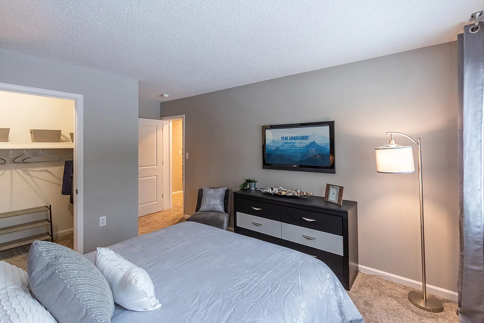 Cozy bedroom with a modern dresser, soft gray tones, and an inviting walk-in closet.