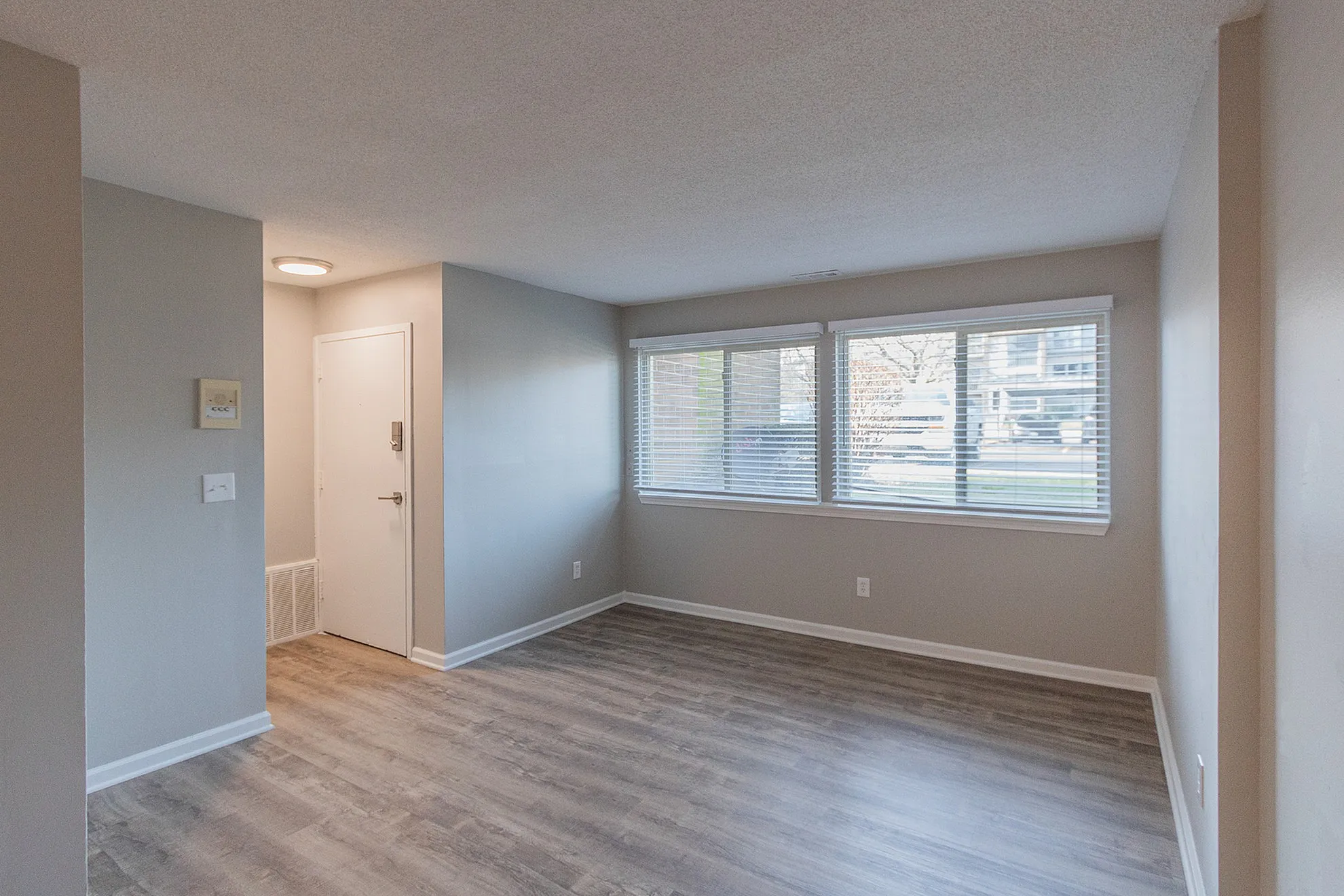Bright, open living space with large windows and modern wood flooring, offering a welcoming and versatile area for relaxation and entertaining.
