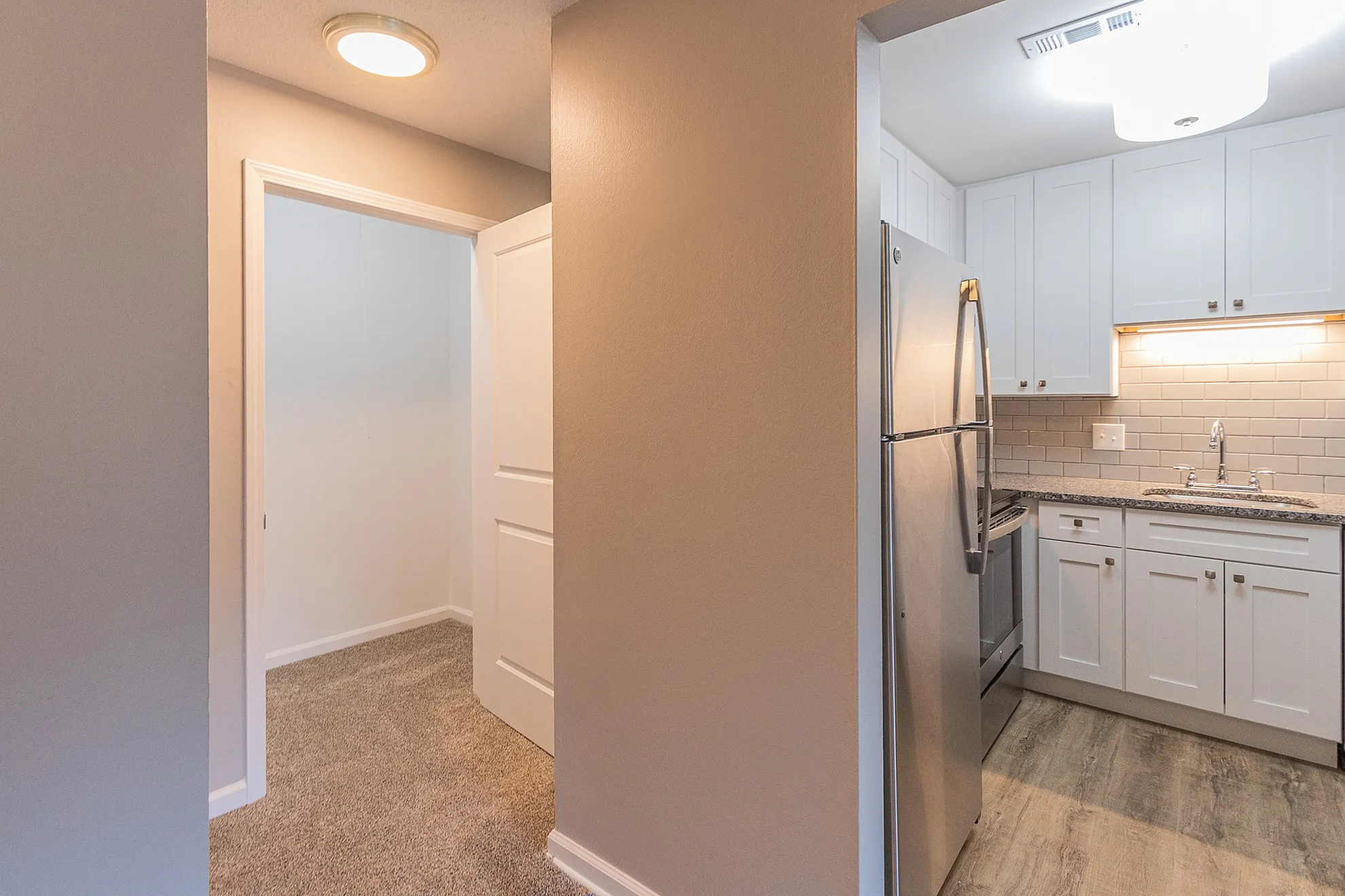 Inviting apartment interior showcasing a modern kitchen with stainless steel appliances, light cabinetry, and sleek tile backsplash.