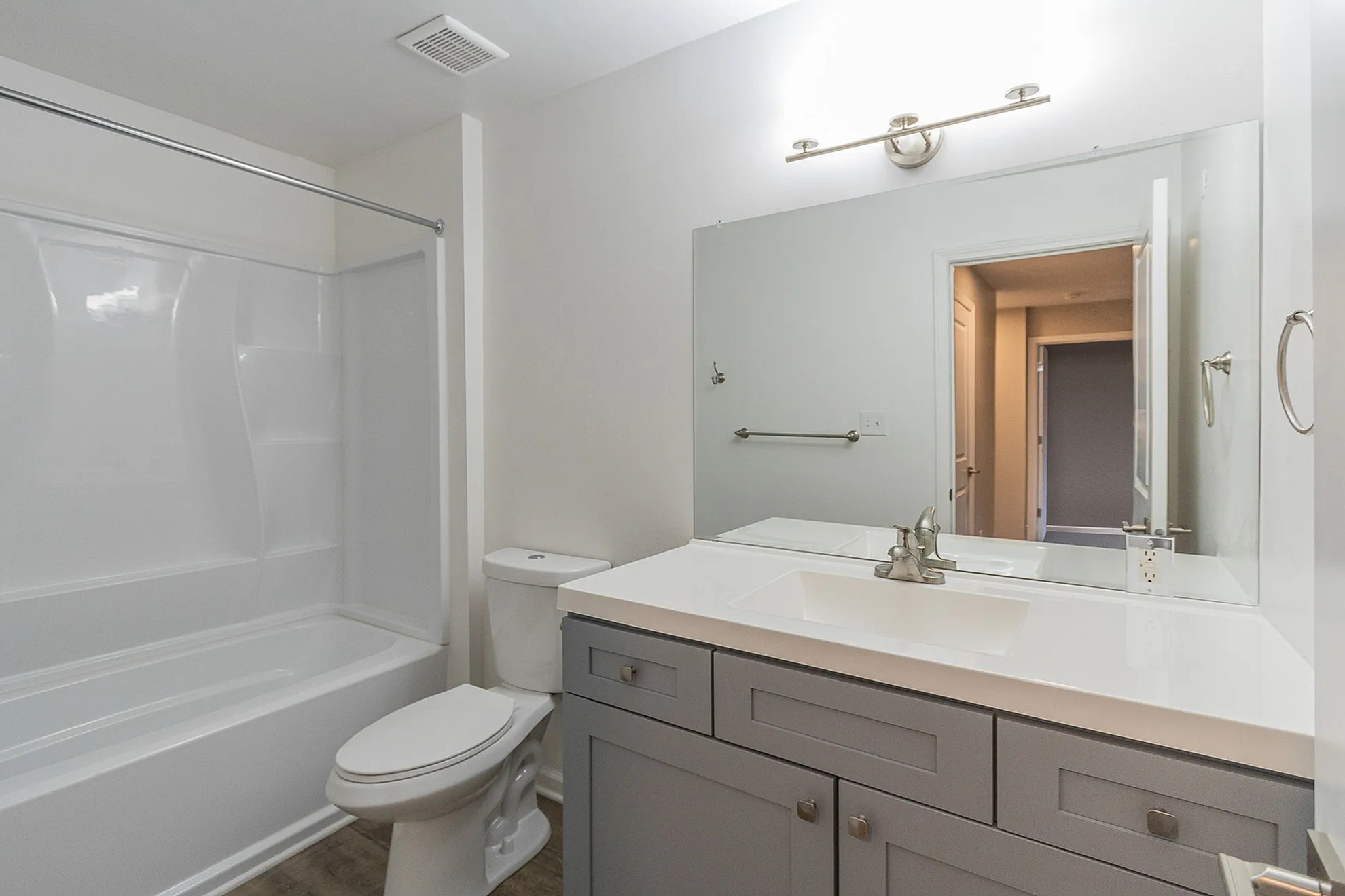 Modern bathroom featuring a sleek vanity, large mirror, and a stylish bathtub with a contemporary showerhead.