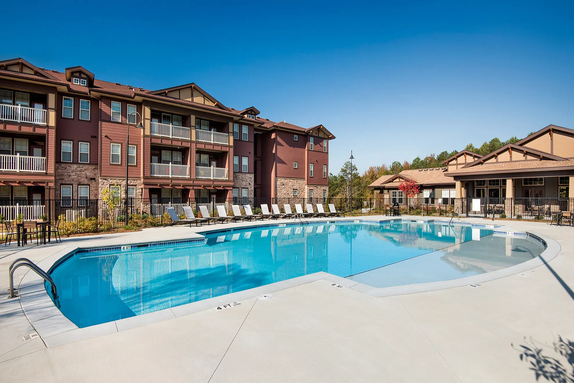 Luxurious apartment complex with a sparkling pool, surrounded by modern architecture and ample sun loungers, perfect for relaxation and leisure.