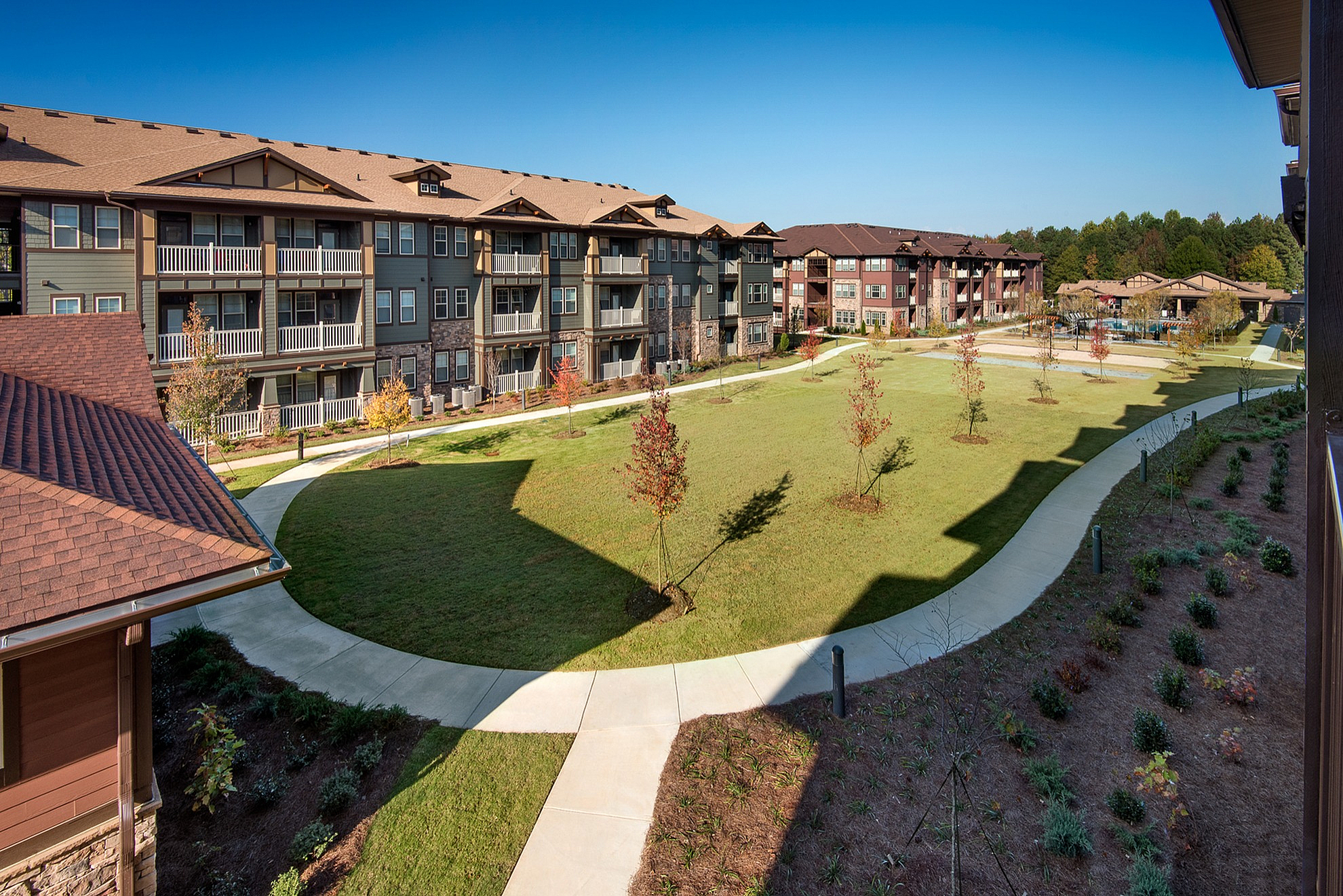 Charming apartment complex surrounded by lush green lawns and scenic pathways, offering a serene living environment.